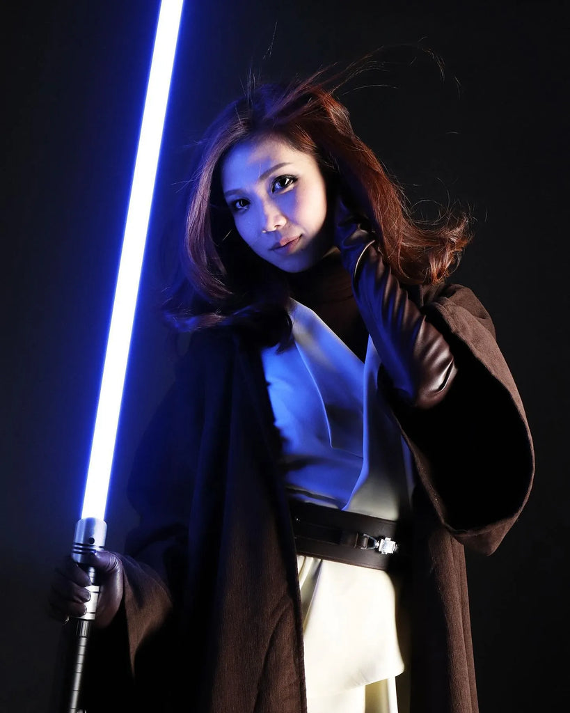 Female Jedi cosplayer holding a Darth Vader-inspired custom neopixel lightsaber with a blue blade