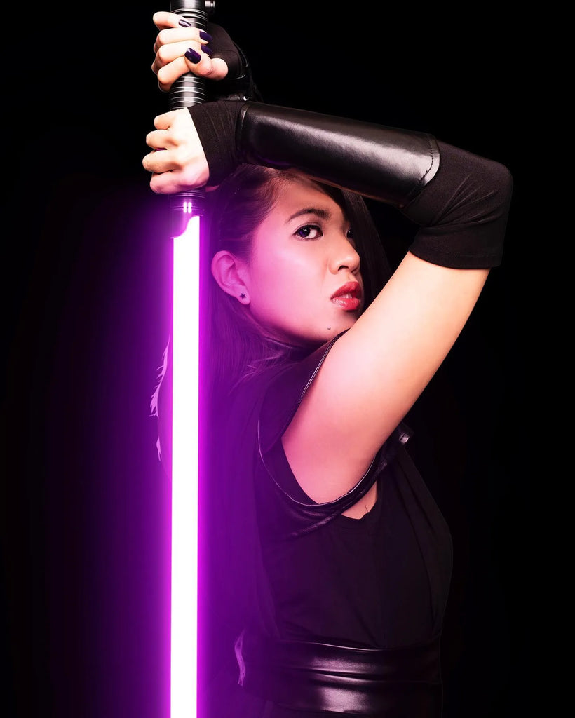 Female Jedi cosplayer holding a Rahm Kota-inspired custom neopixel lightsaber with a purple blade