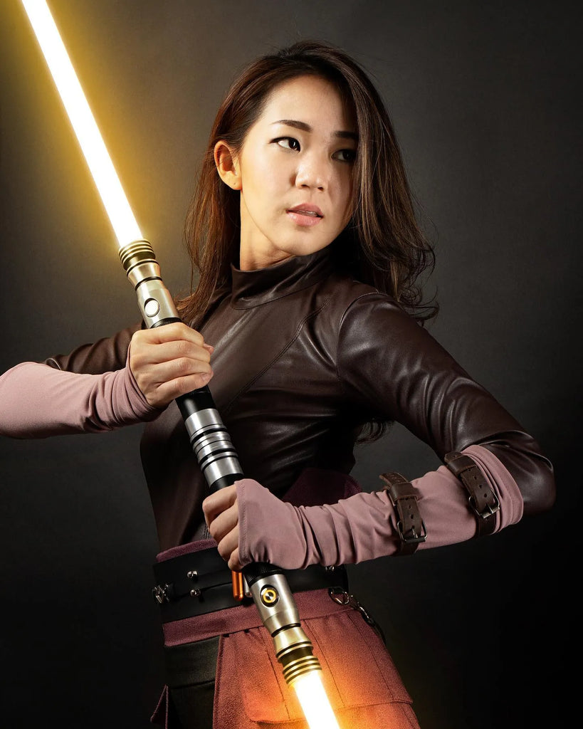Female Jedi cosplayer wielding a custom neopixel saberstaff with amber blade.