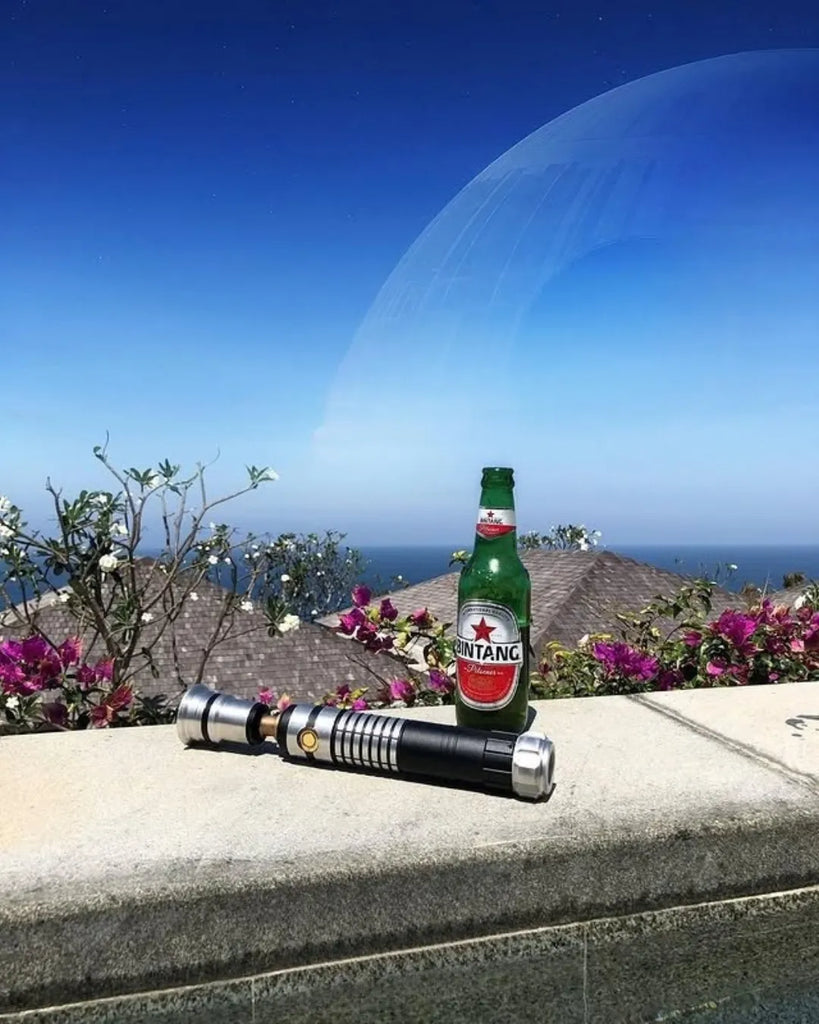 A lightsaber and beer bottle on a tropical ledge with the Death Star looming in the sky