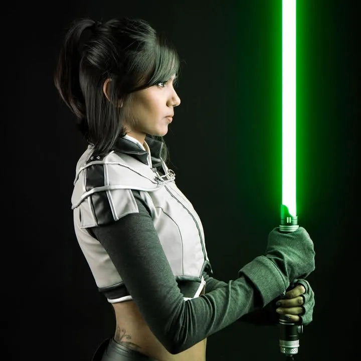A female Jedi cosplayer looking intensely while holding a Rahm Kota-inspired custom neopixel lightsaber with green blade