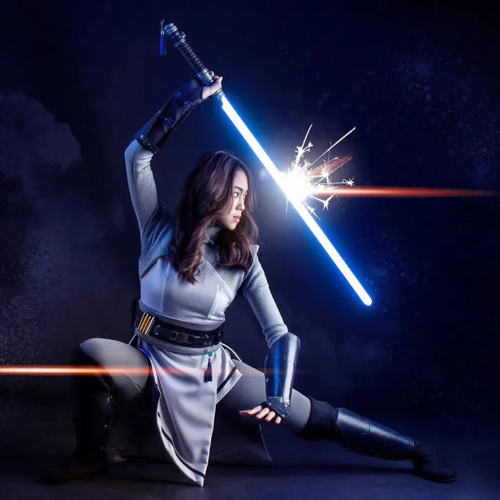 Female Jedi cosplayer in a defensive stance, deflecting an attack with a blue lightsaber