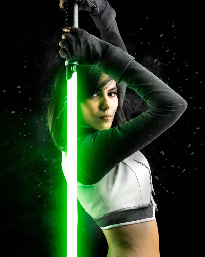 A female Jedi cosplayer looking intensely while holding a Rahm Kota-inspired custom neopixel lightsaber with green blade