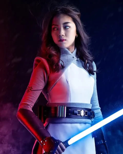 Female Jedi cosplayer holding a rahm Kota-inspired custom neopixel lightsaber with blue blade, illuminated by contrasting red