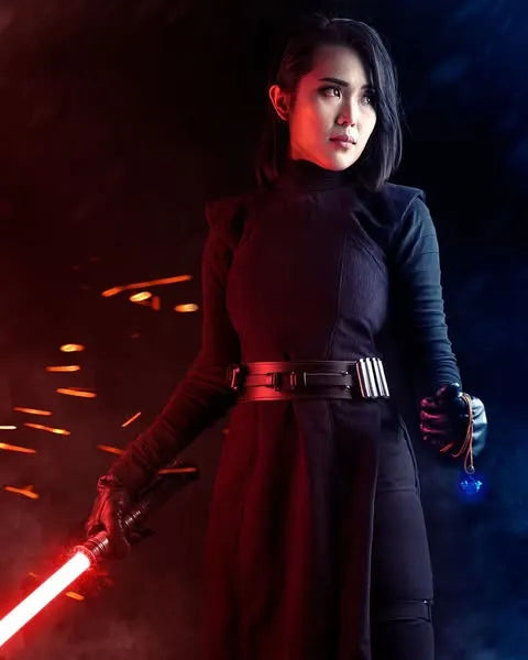 Female Sith cosplayer in dark robes holding Luke Skywalker-inspired custom neopixel lightsaber with an ignited red blade