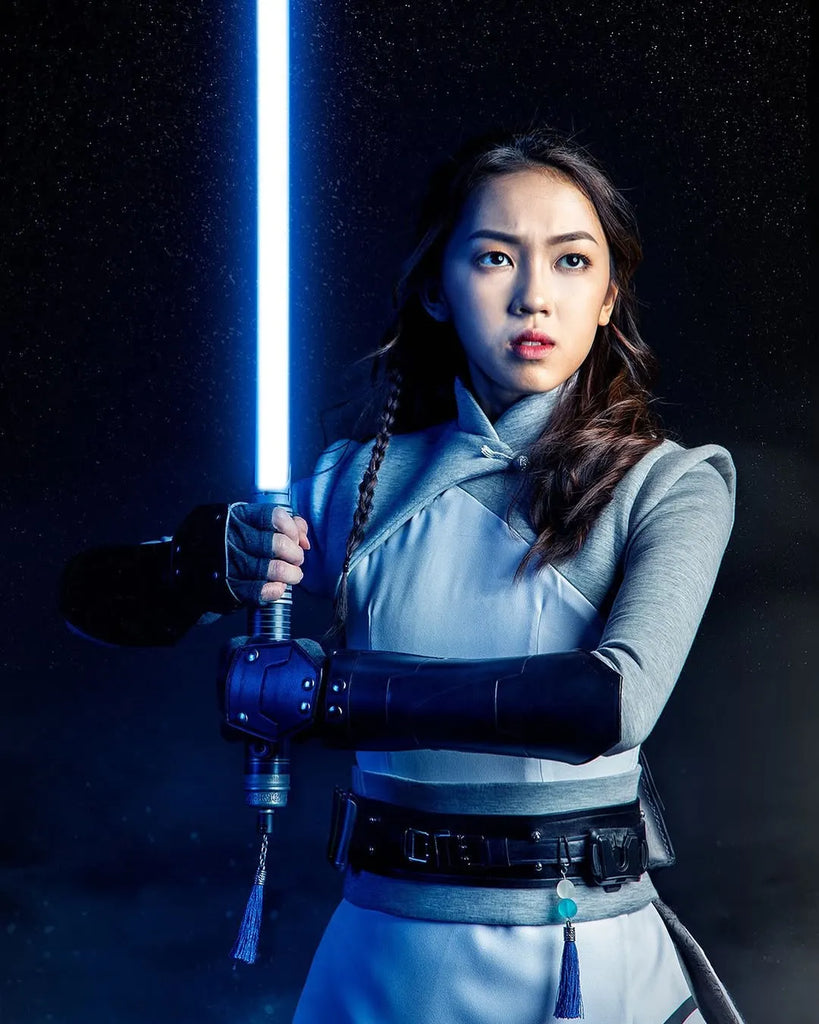 Female Jedi-inspired cosplayer holding a Rahm Kota-inspired custom neopixel lightsaber with a blue blade