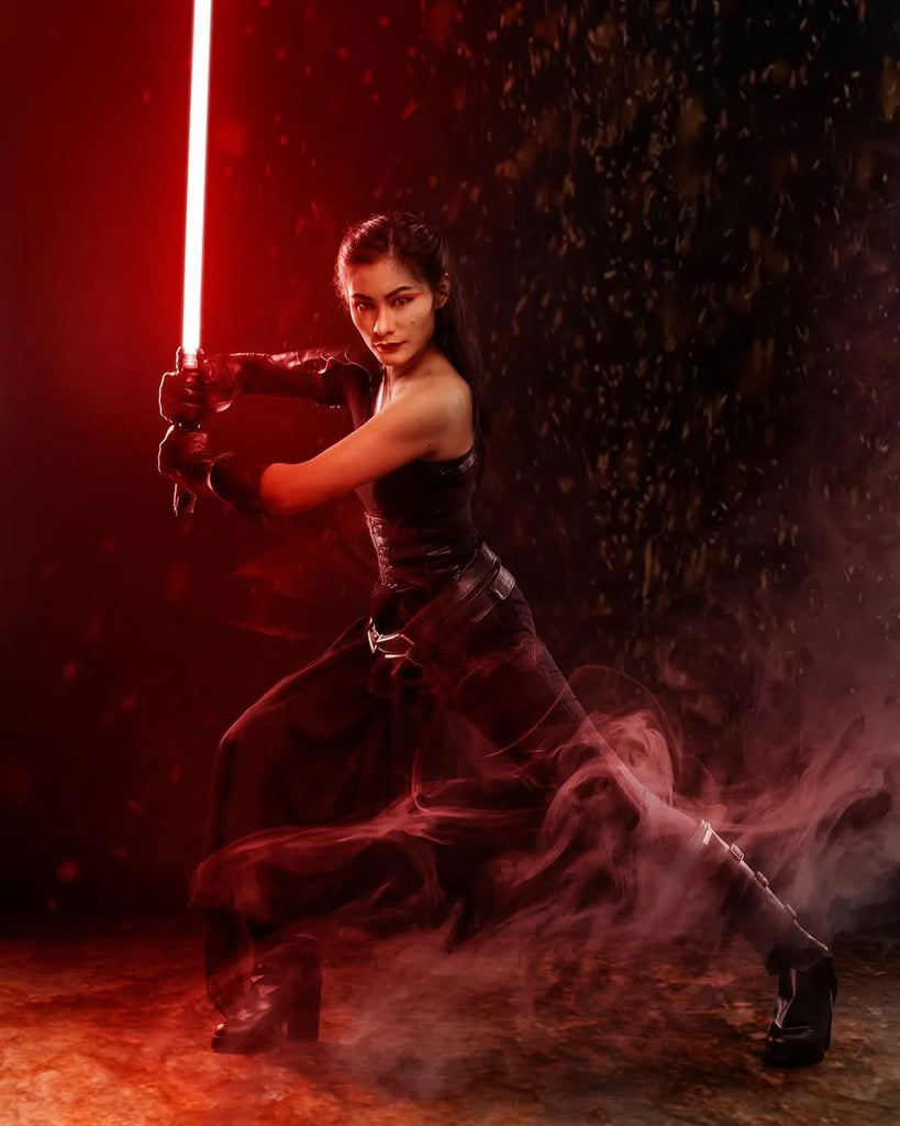 Female Sith-inspired cosplayer holding a Sith-inspired custom neopixel lightsaber with a red blade