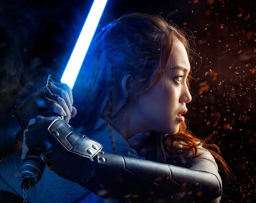 Female Jedi-inspired cosplayer holding a Rahm Kota-inspired custom neopixel lightsaber with a blue blade while facing a contrasting red light