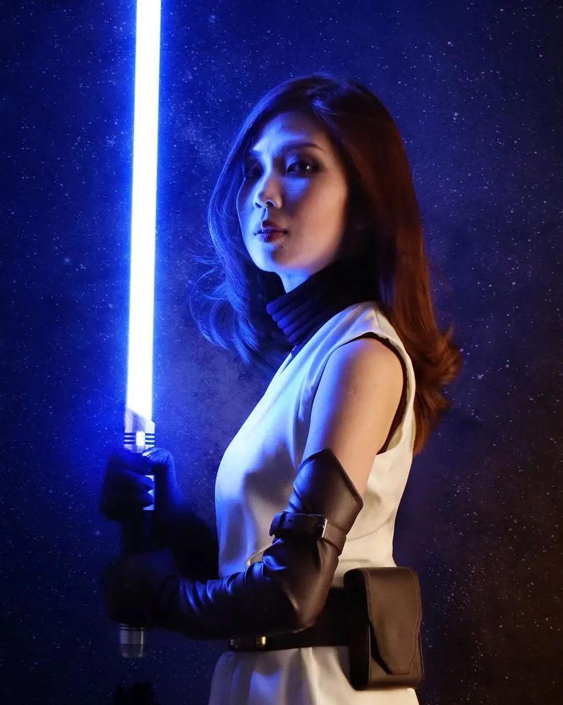 Female Jedi-inspired cosplayer holding a Darth Vader-inspired custom neopixel lightsaber with a blue blade
