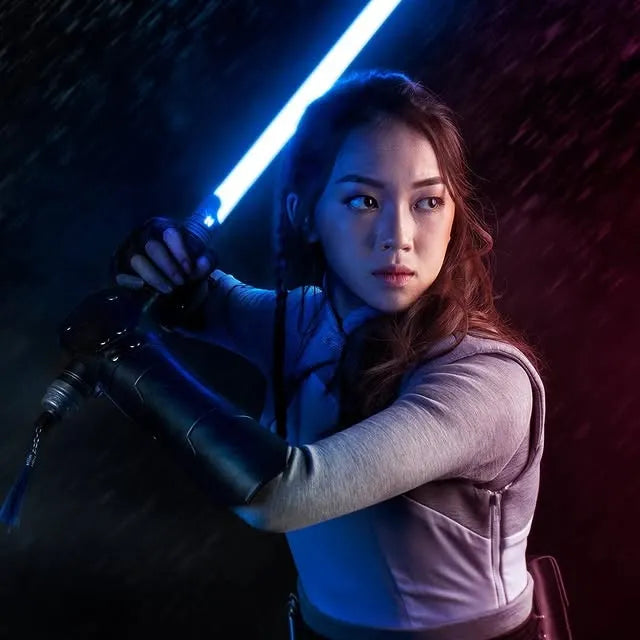 Female Jedi-inspired cosplayer holding a Mirah, a Rahm Kota-inspired custom neopixel lightsaber with a blue blade