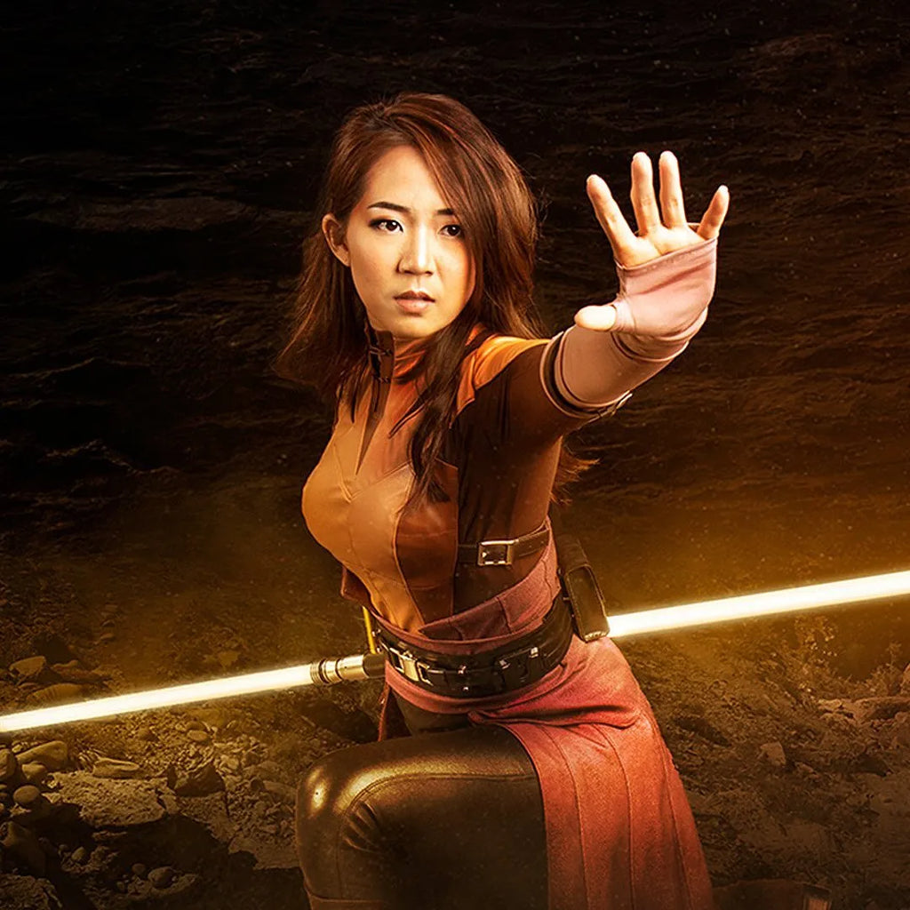 Bastila shan-inspired cosplayer kneeling with one hand extended while holding a Clone Wars-inspired custom neopixel saberstaff with yellow blade