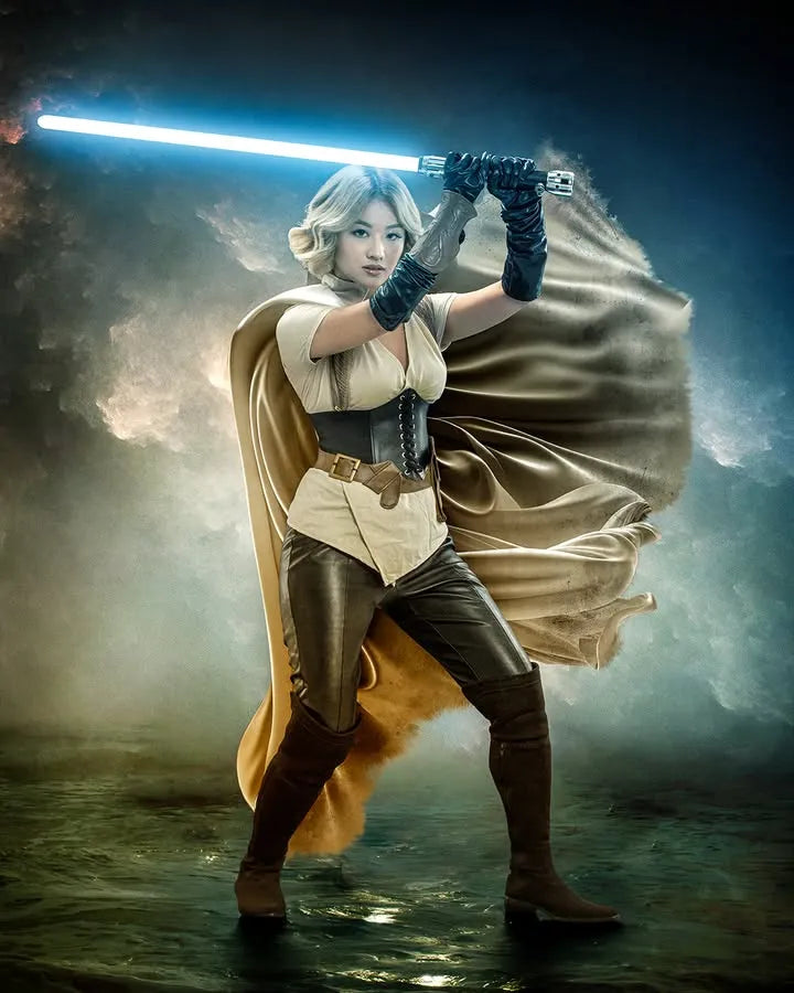 Female Jedi-inspired cosplayer holding a Ben Solo-inspired custom neopixel lightsaber with a blue blade on a stormy landscape